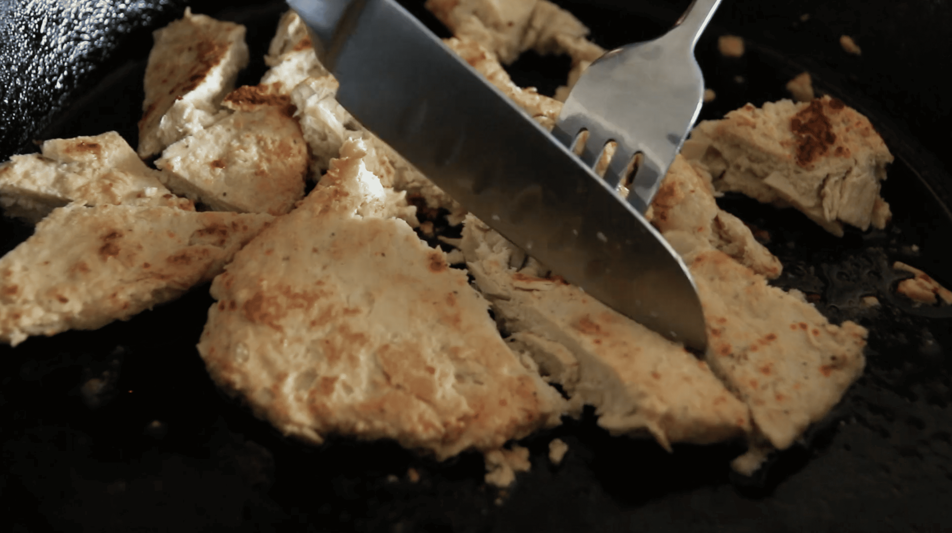 fork and knife cutting into chicken