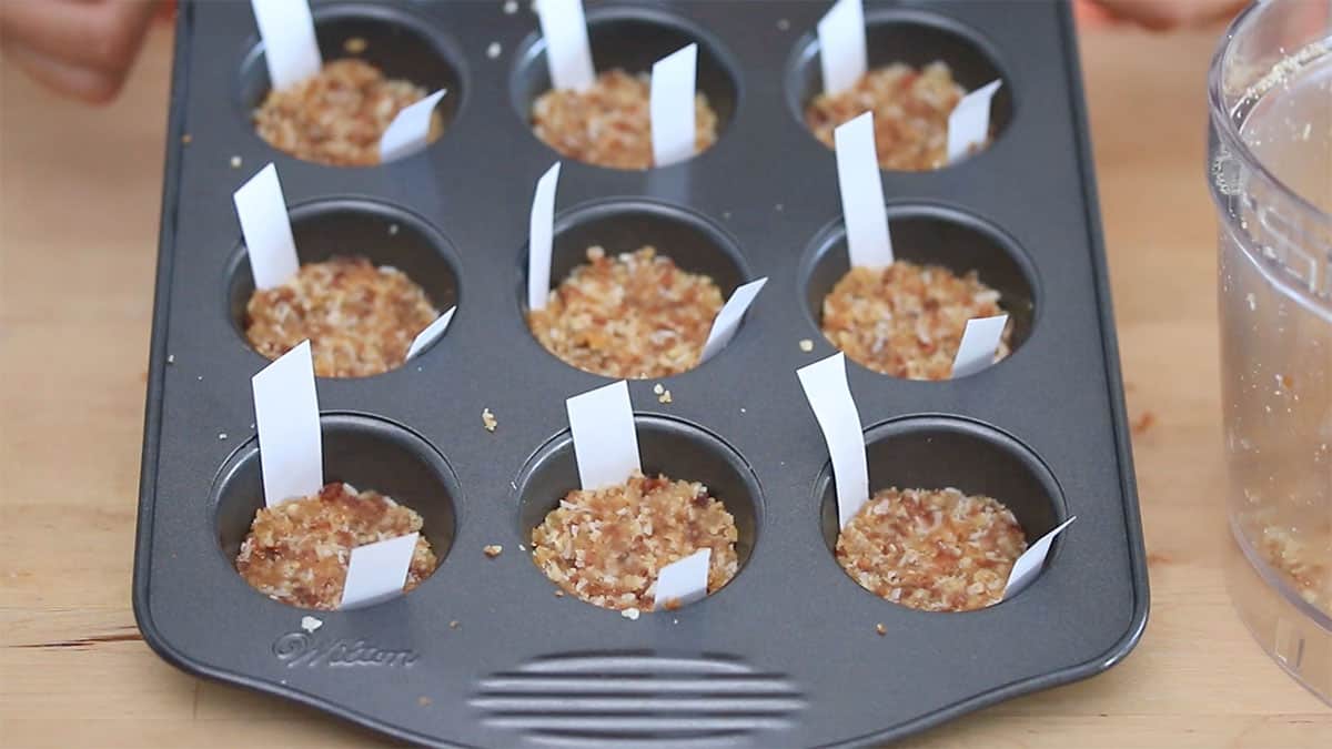 a mini muffin pan with walnut crust pressed into the cups
