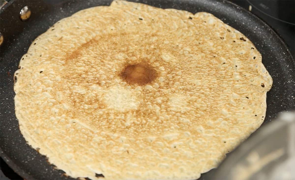 one side of a crepe being cooked on a crepe pan