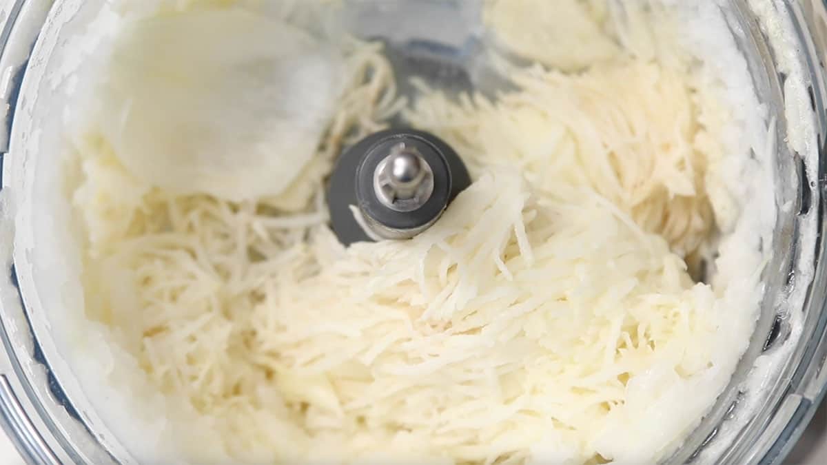 overhead of food processor with shredded potato in it