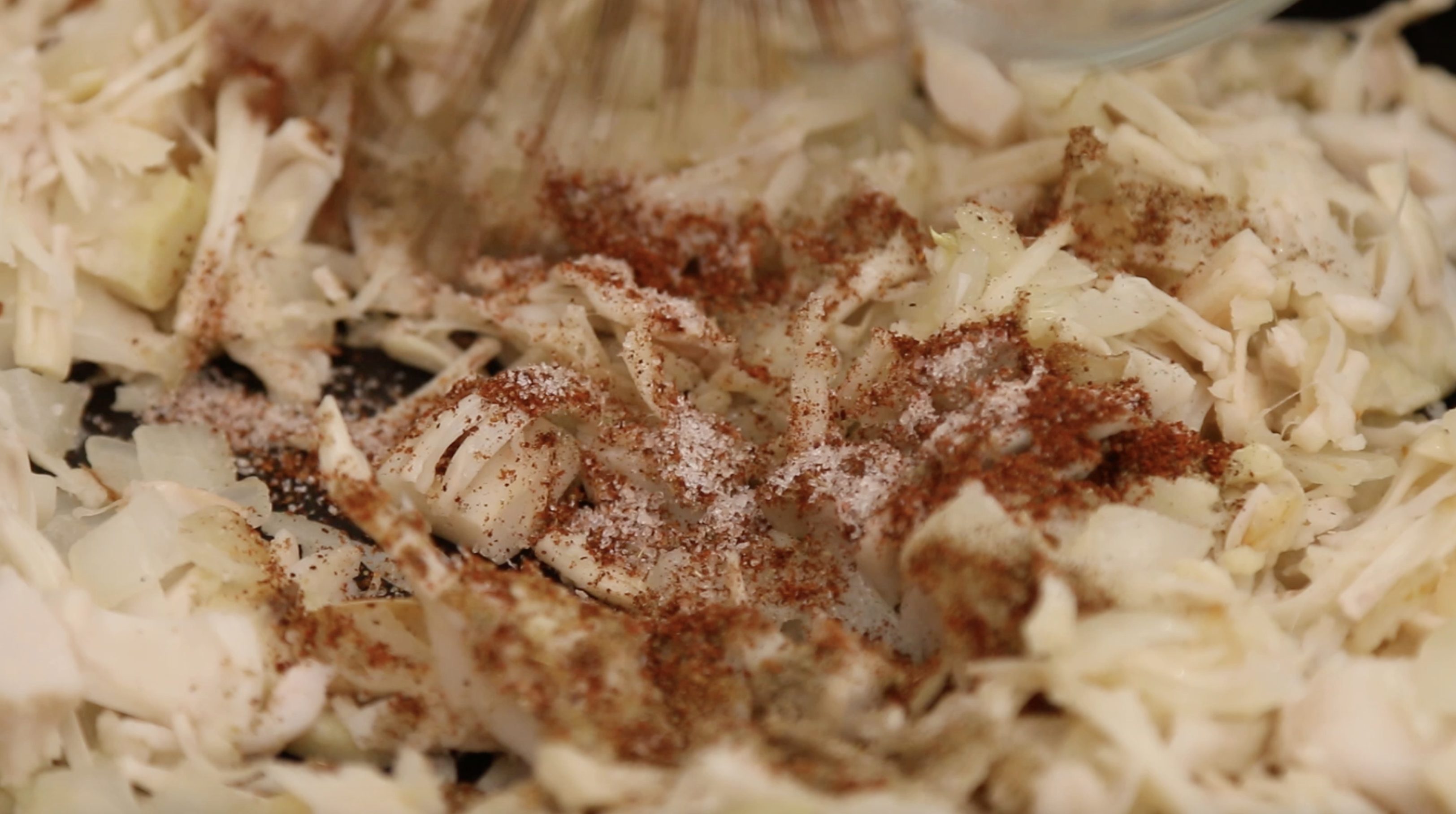 spices being added to jackfruit in a pan