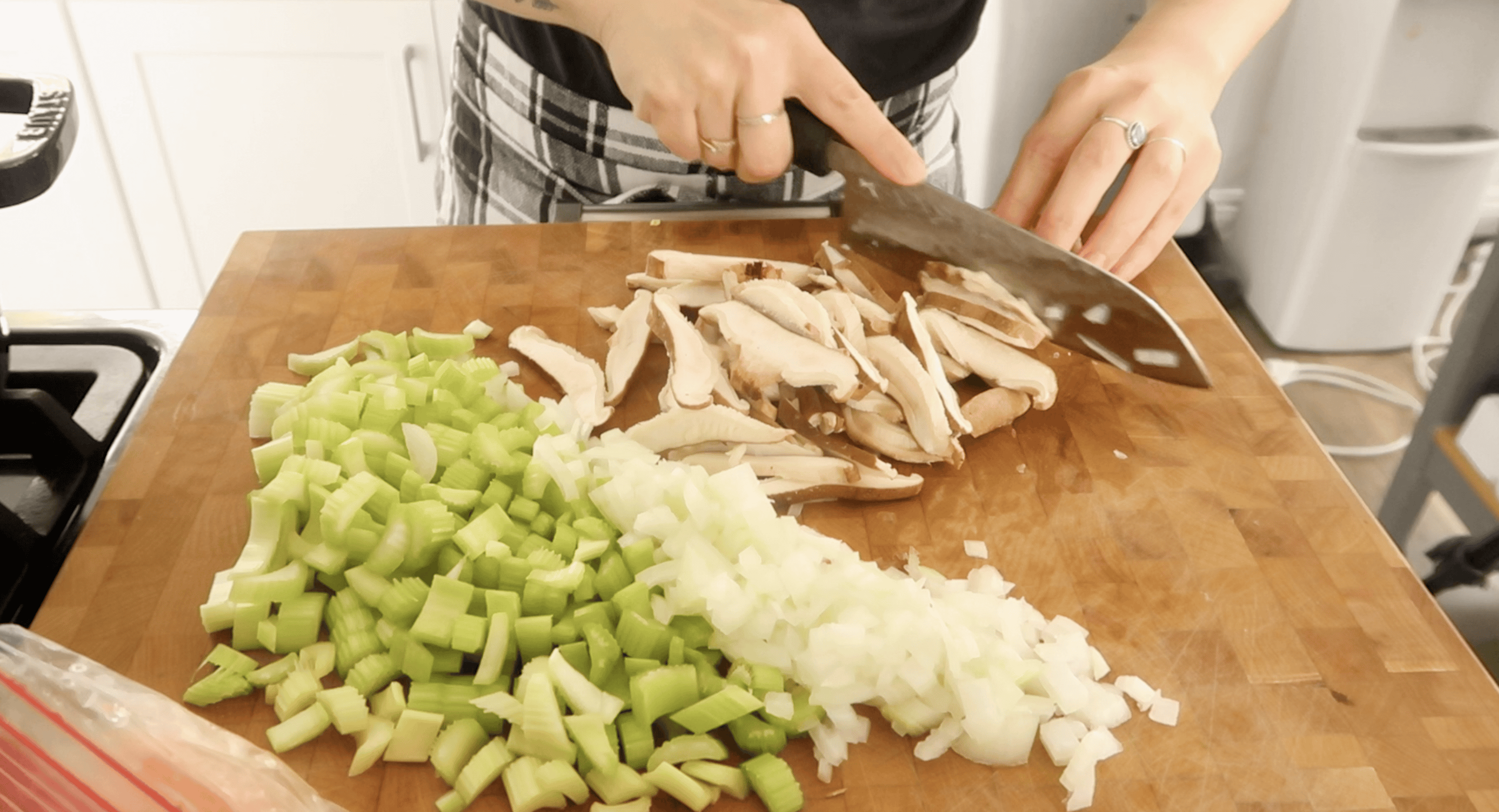 a cutting board with chopped celery, onion and shitake mushrooms on it