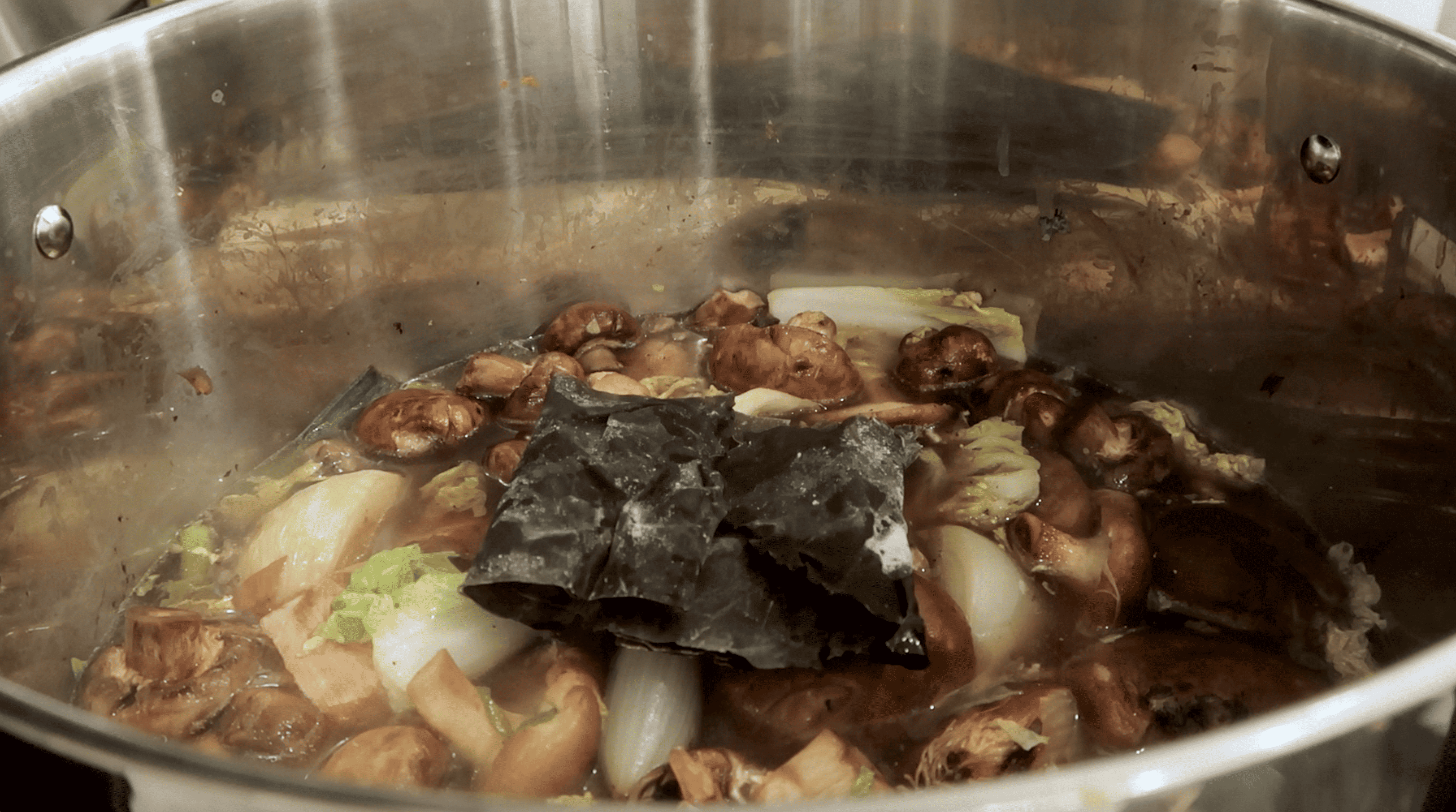 adding kombu to a stockpot of broth