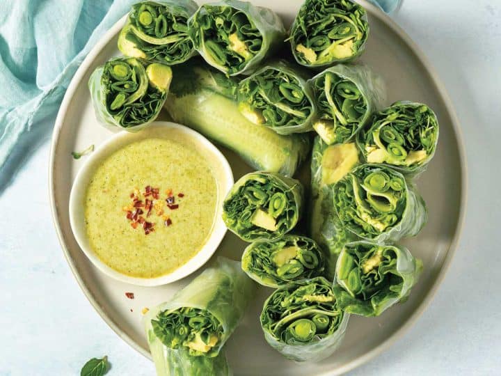overhead of a plate of halved green fresh rolls with dipping sauce