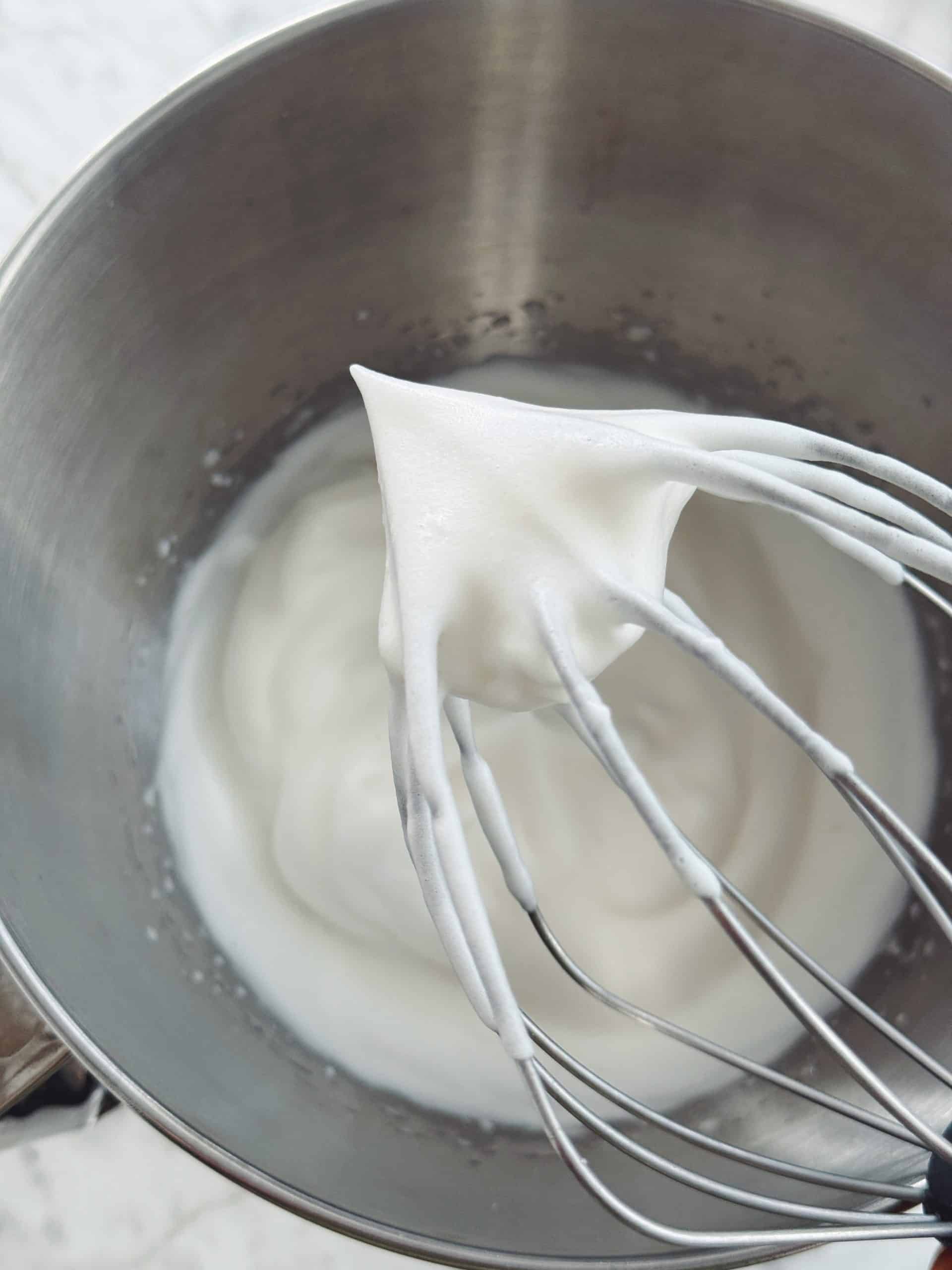 overhear of whisk and mixing bowl showing stiff peaks of aquafaba